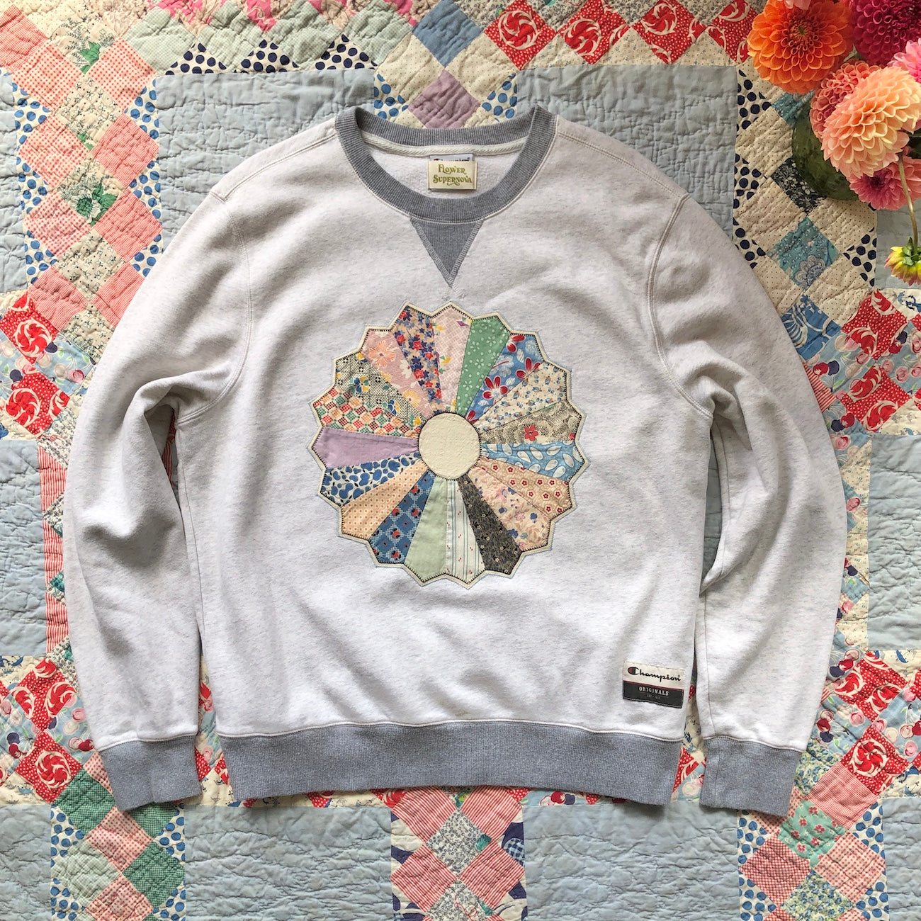 Gray crewneck sweatshirt with Dresden Plate vintage quilt patch sewn to front by Flower Supernova.