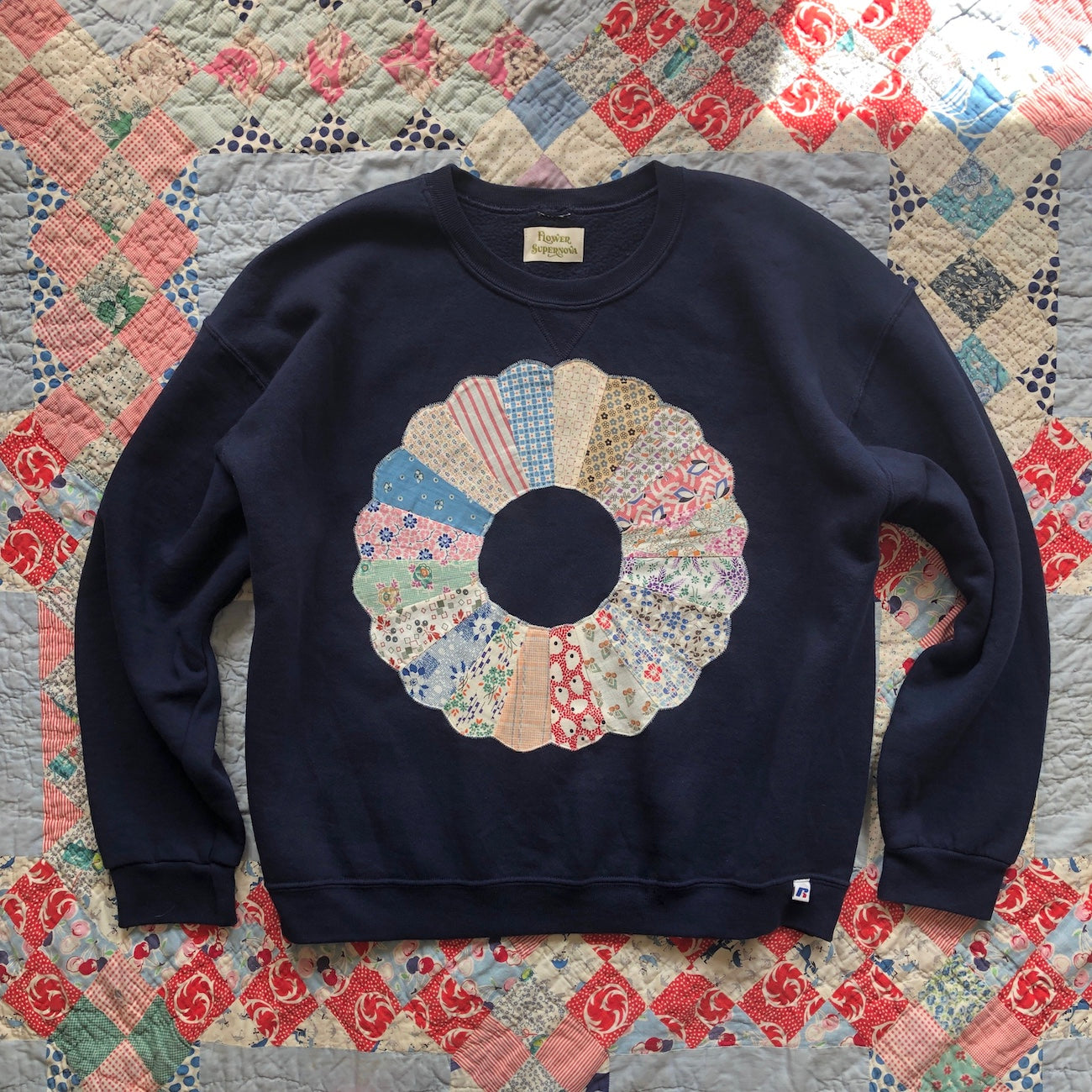 Navy blue crewneck sweatshirt with Dresden Plate vintage quilt patch sewn to front by Flower Supernova.
