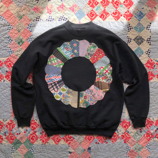 Black crewneck sweatshirt with Dresden Plate vintage quilt patch sewn to front by Flower Supernova.